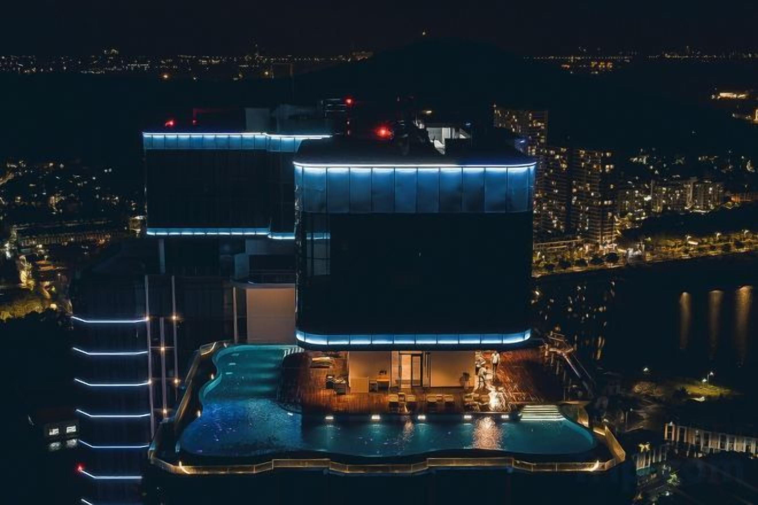 Ein mehrstöckiges Hotel mit Poolbereich, das einen markanten Dachterrasse mit Blick auf die Stadtlandschaft bietet.
