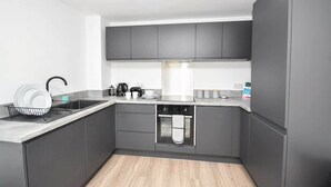 Una cucina moderna con mobili grigi, un lavello in acciaio inossidabile e un forno integrato.