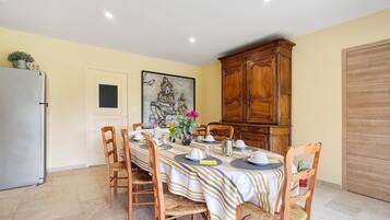 Een eetruimte met een tafel gedekt voor vier personen, omringd door houten stoelen, een kast en een koelkast.