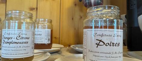 Tres tarros de vidrio con mermelada sobre platos blancos, con etiquetas que dicen 'Confiture Extra' y 'Poires'.