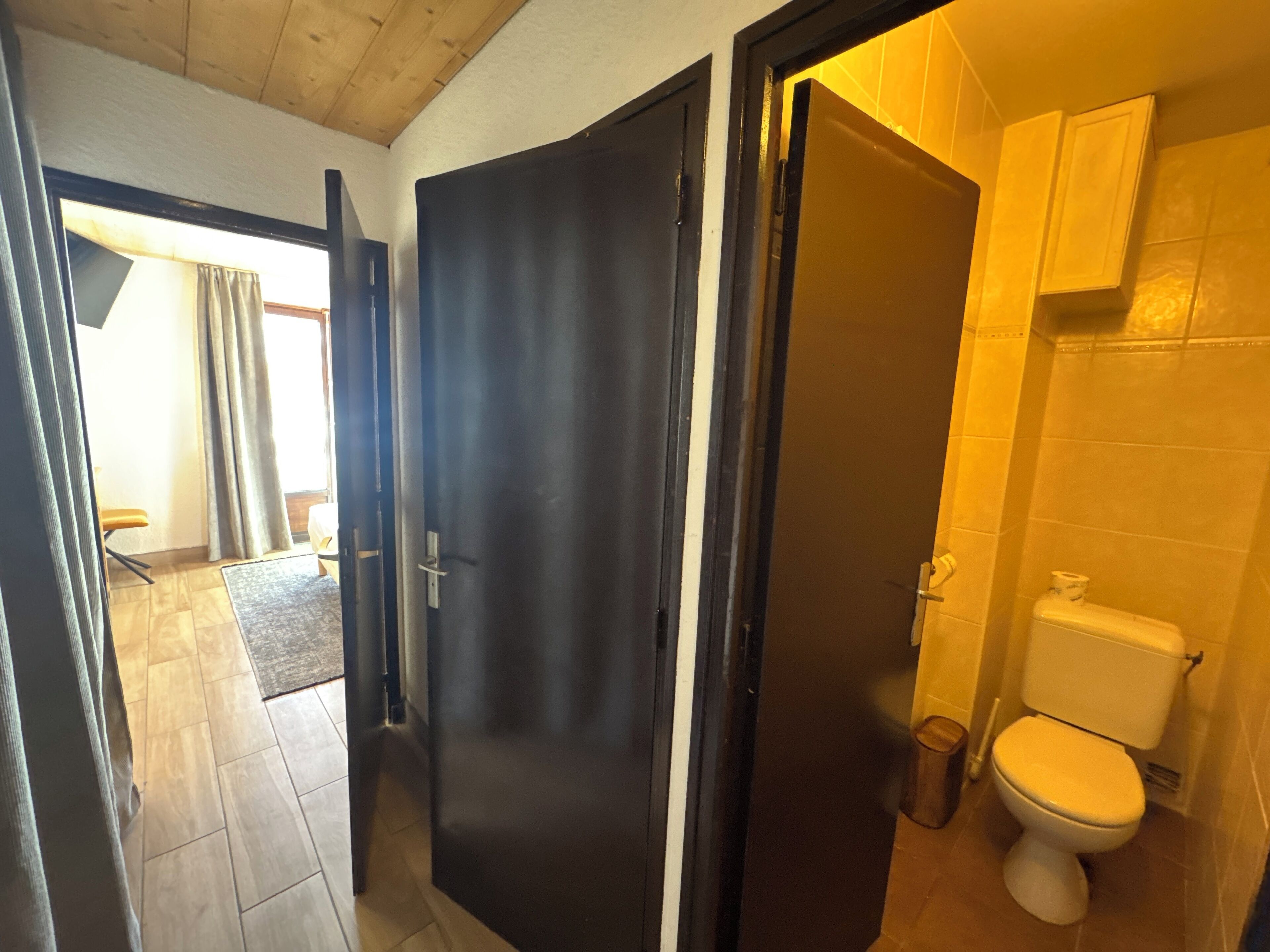 A bathroom with a toilet, a sink, and a cabinet. There is a door leading to another room.