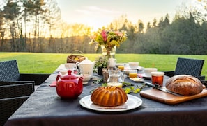 A picnic setup with a table, chairs, a red teapot, a bundt cake, a loaf of bread, and a pitcher of water. - Guest Room Périgord Noir - 2 Persons (Fleurac)