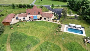 Ein geräumiges Haus mit Schwimmbad, überdachter Terrasse und gepflegtem Rasen.