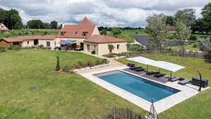 Ein Wohnhaus mit Swimmingpool, Sitzgelegenheiten im Freien und einem großen Haus mit Ziegeldach.