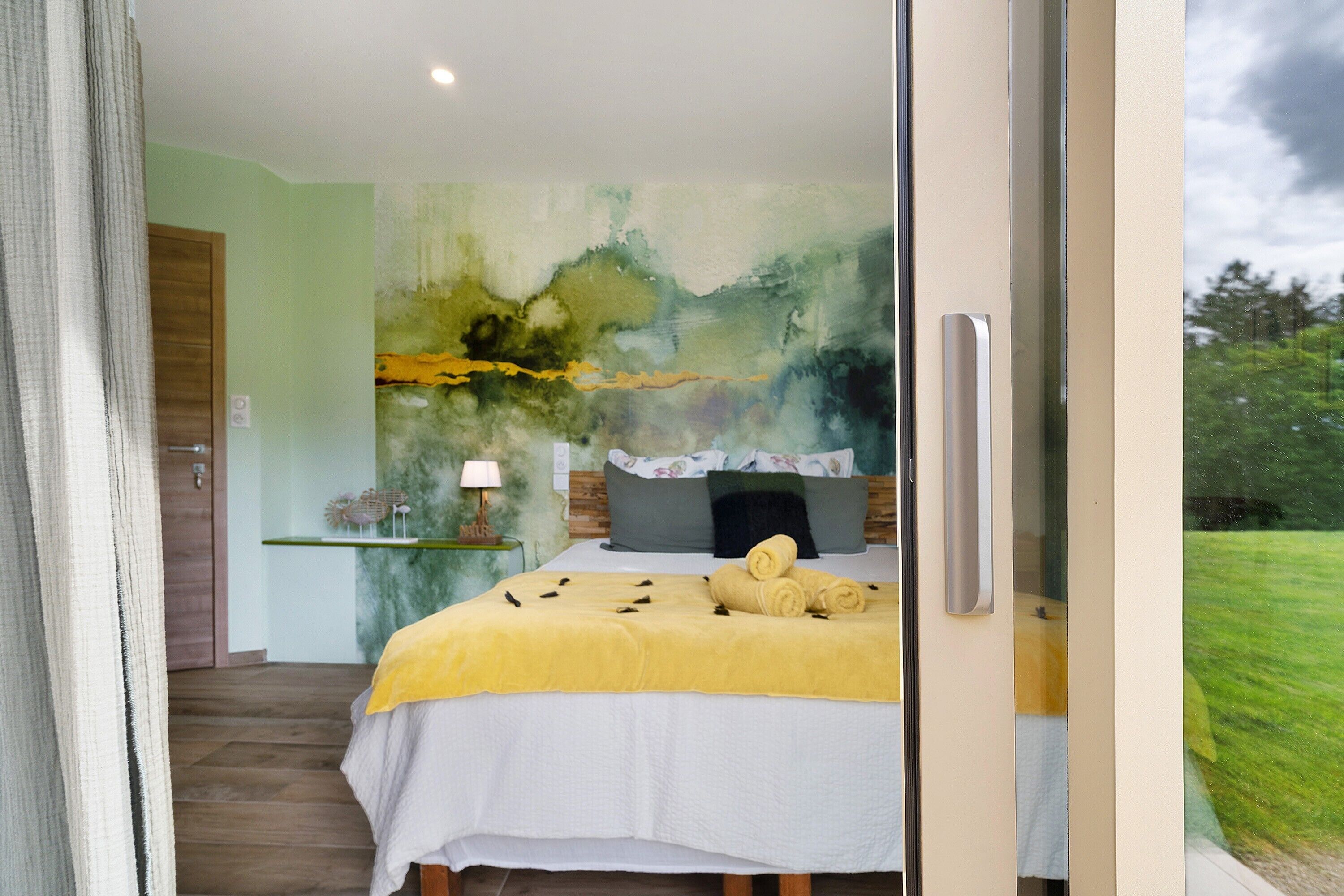 Une chambre à coucher avec un lit, une table de chevet, une lampe et une vue sur l’extérieur.