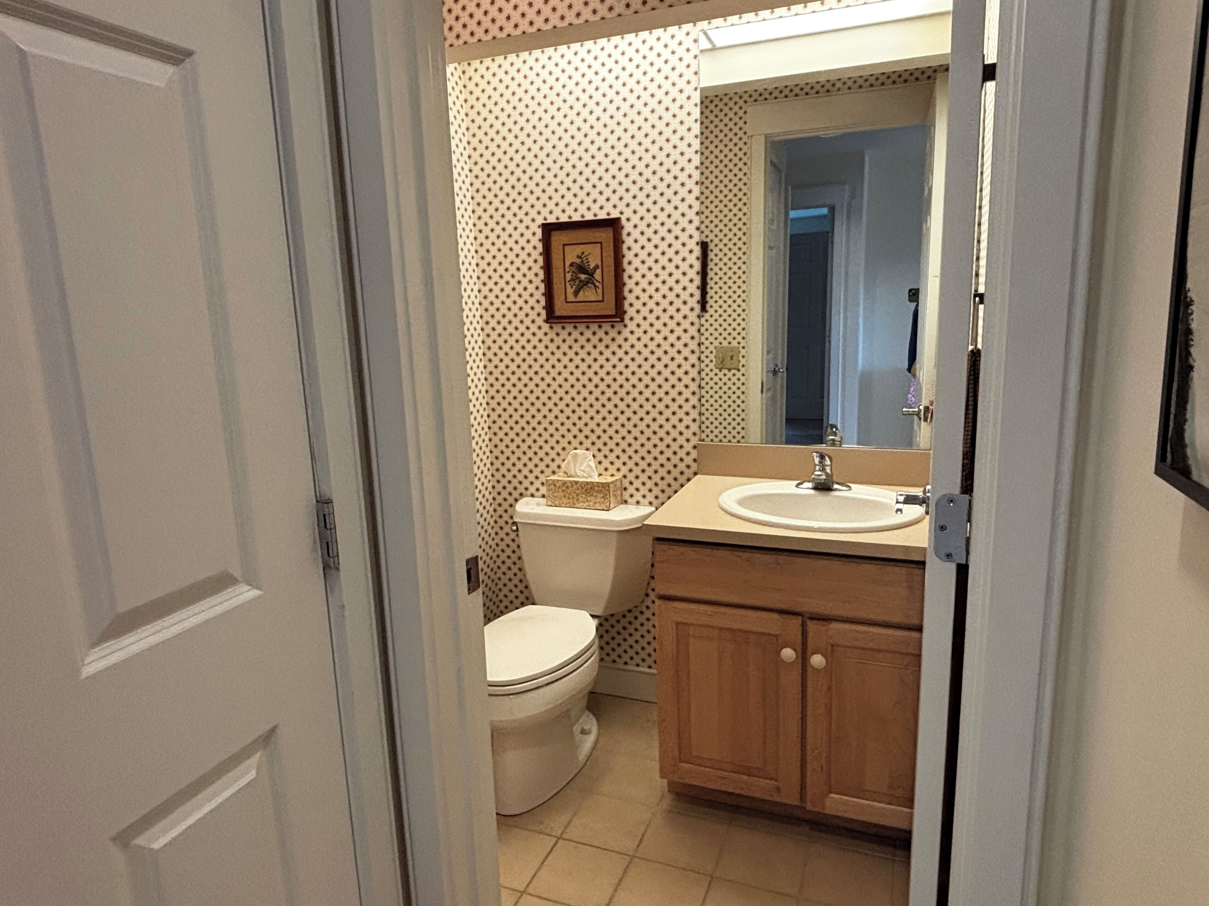 A bathroom with a toilet, sink, and cabinet.