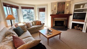 A cozy living room with a sofa, a coffee table, a fireplace, and a TV.