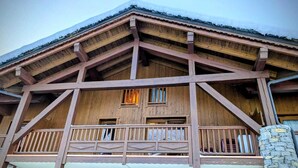 Un chalet en bois doté d’un balcon et de nombreuses fenêtres.