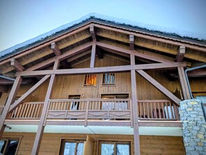 Un chalet en bois doté d’un balcon et de nombreuses fenêtres.
