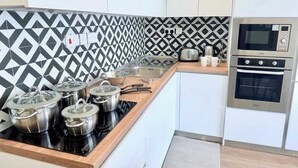 A modern kitchen with a black and white patterned backsplash, stainless steel appliances, and white cabinetry. - The Bugibba Central Penthouse! (Saint Paul's Bay)