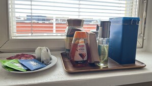 A window sill with a plate of snacks, a jar of spices, a bottle of water, and a blue container. - Magnificent 1-bedroom apartment in Kouvola city centre (Kouvola)