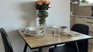 A dining area with a table set for two, a vase of flowers, and a framed picture on the wall. - Magnificent 1-bedroom apartment in Kouvola city centre (Kouvola)
