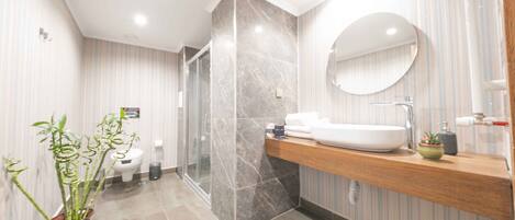 A modern bathroom with a marble shower, a wooden vanity, and a large mirror.