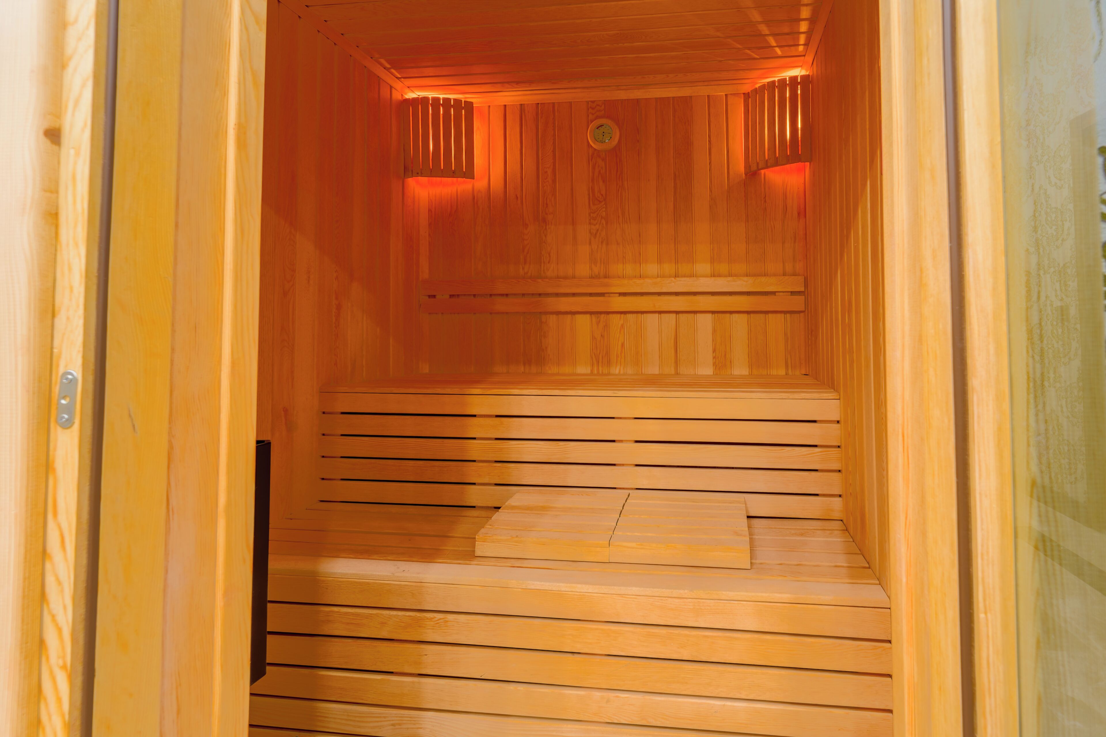 Una sauna de madera con un banco y una puerta.