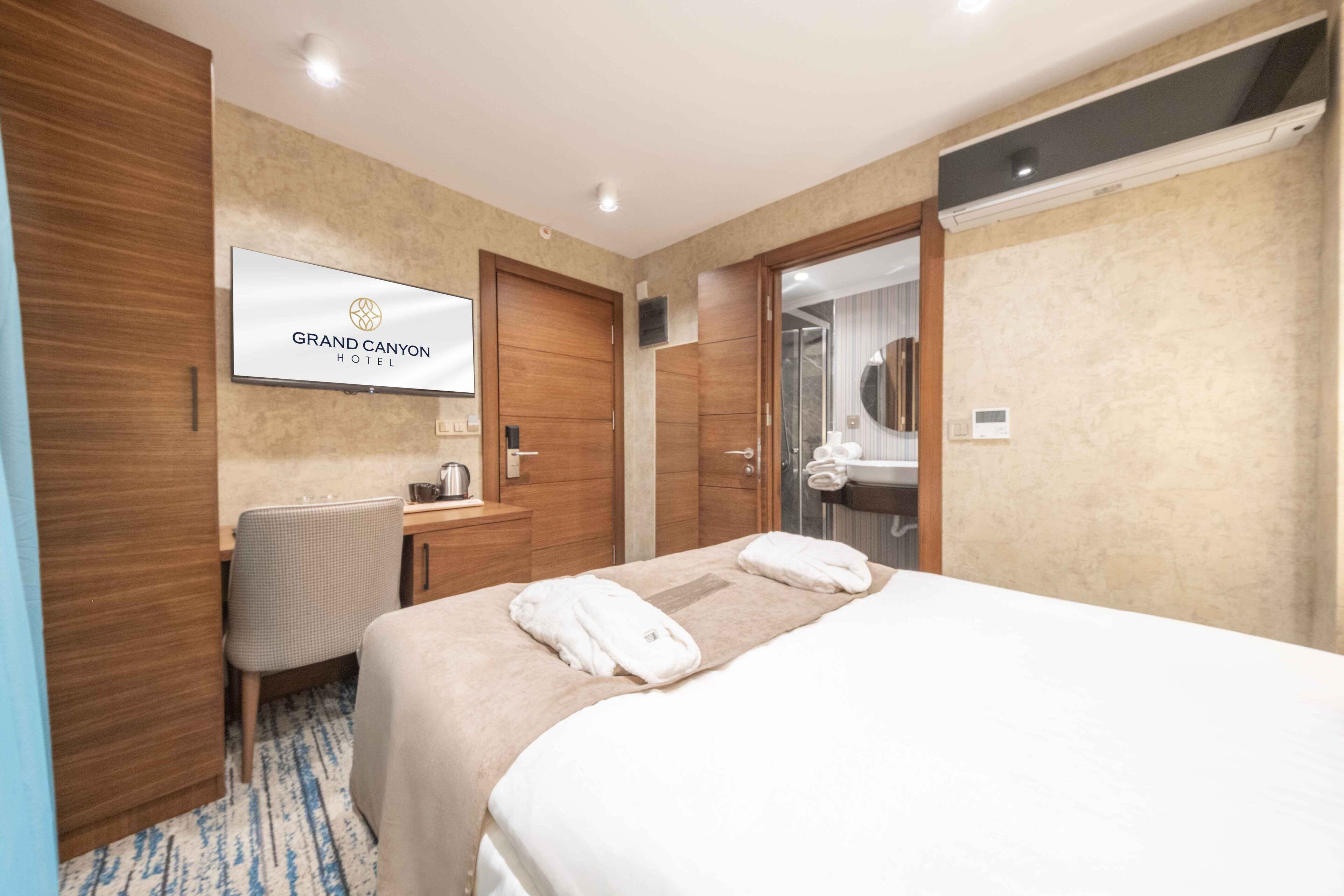 Una habitación de hotel con cama, escritorio, silla, televisor y espejo.