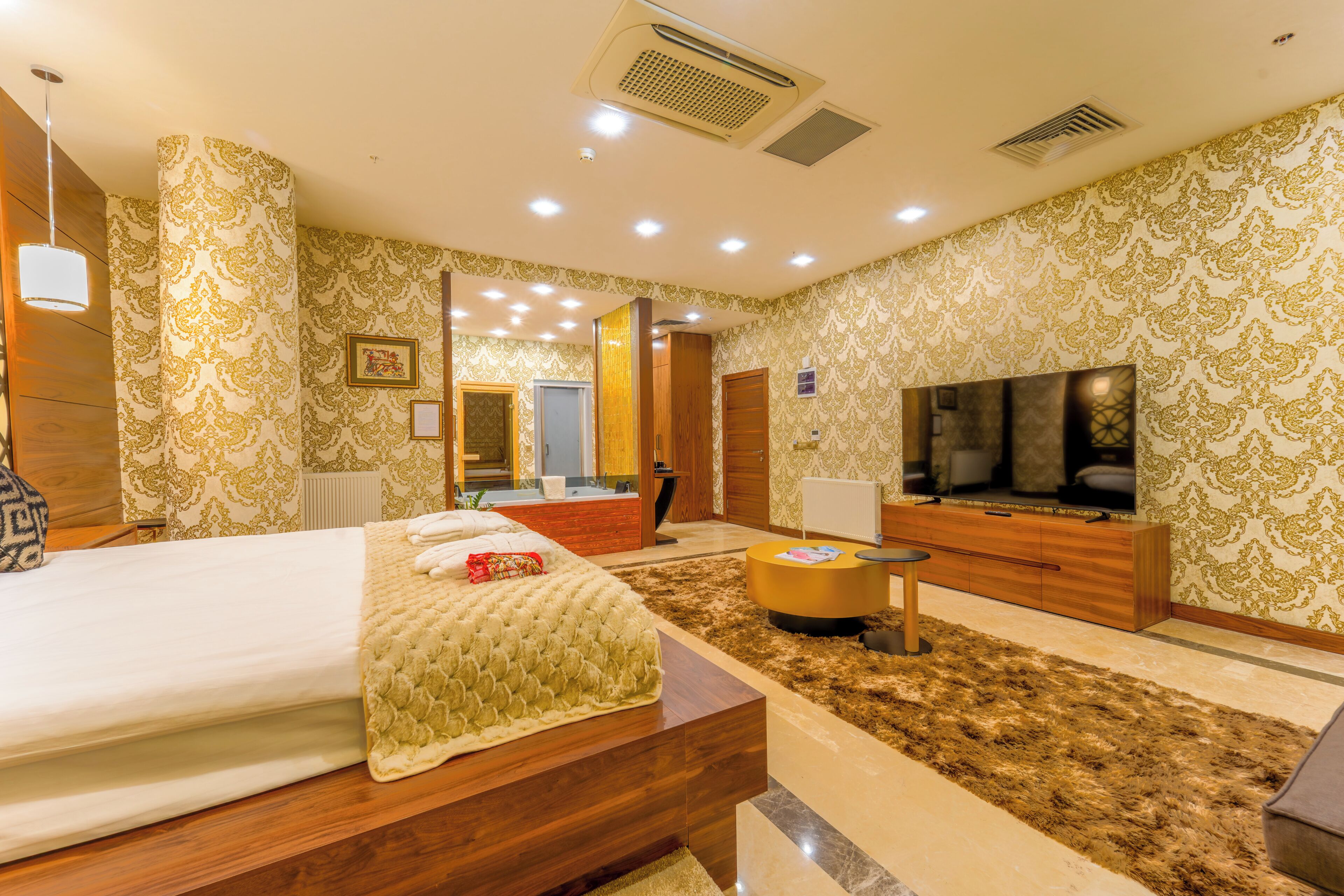 A hotel room with a bed, a TV, a wooden cabinet, and a mirror.