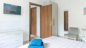 Ein Schlafzimmer mit Bett, Schrank, Schreibtisch und Stuhl.