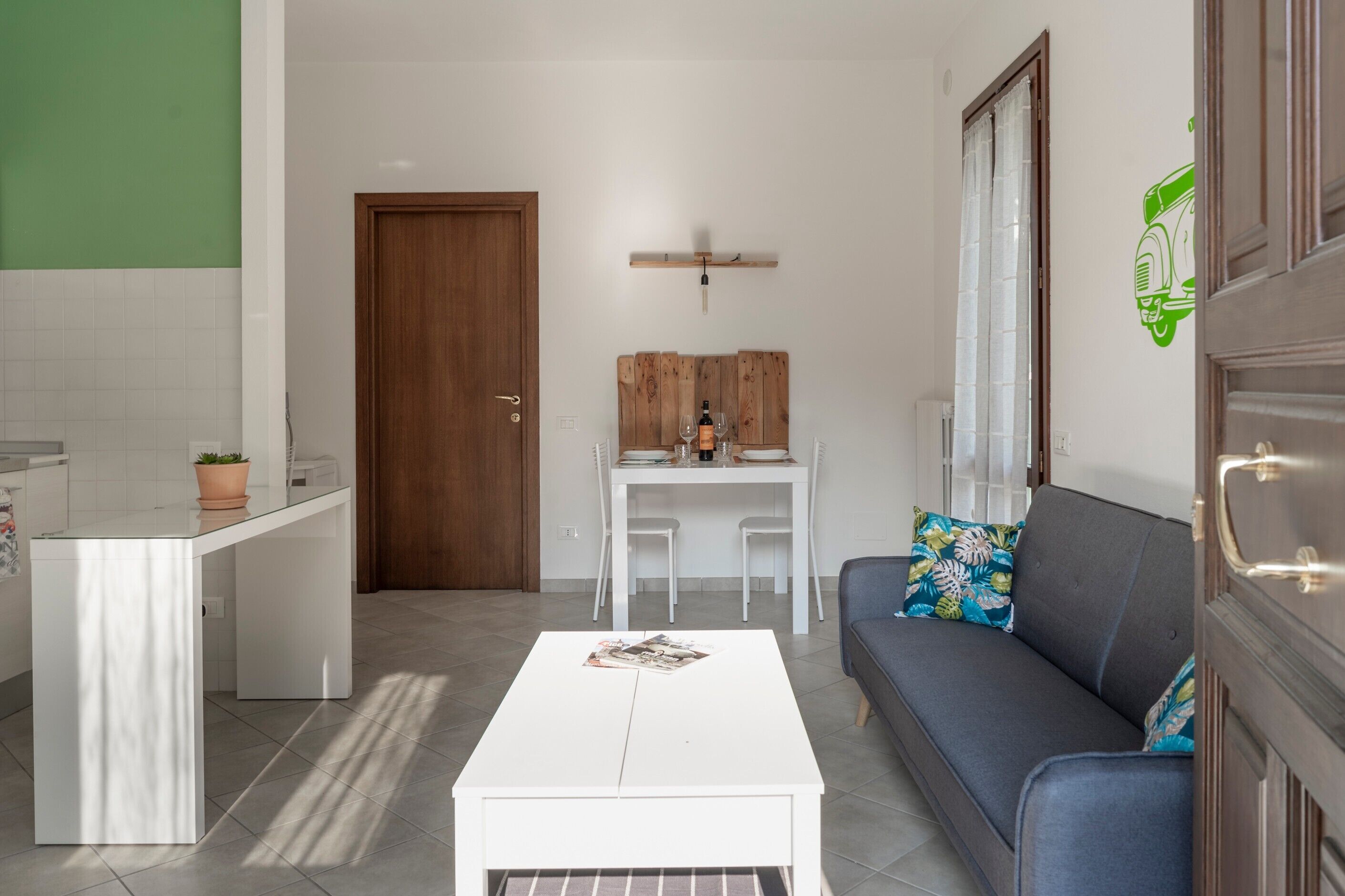 Un salon moderne avec une table basse blanche, un canapé gris et un coin repas agrémenté d’une tête de lit en bois.