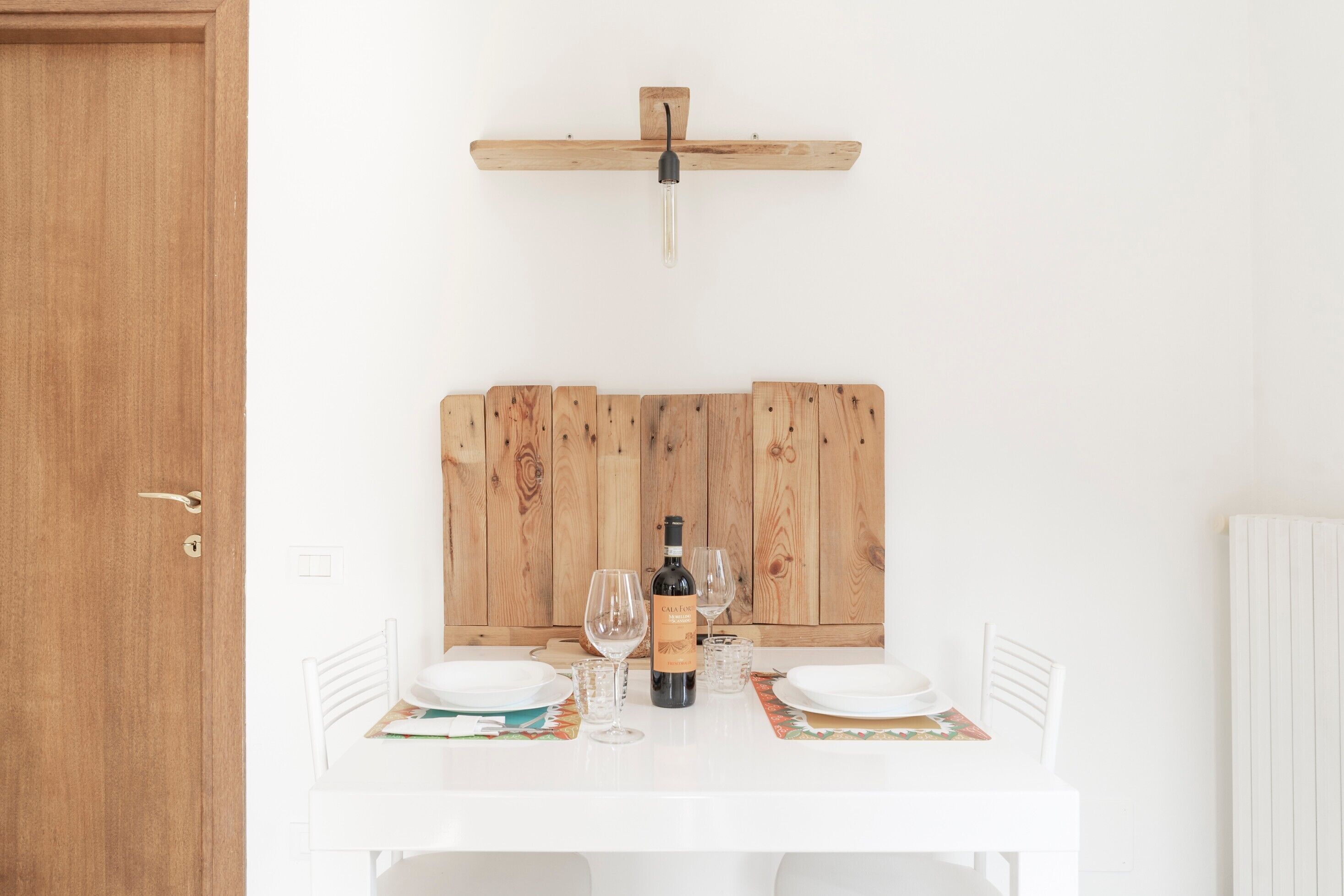 Une table à manger avec une bouteille de vin, des verres et des assiettes, le tout disposé sur un fond en bois.
