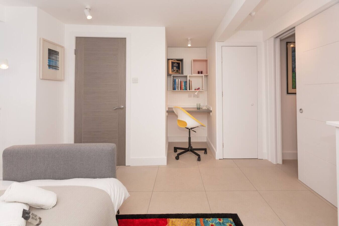 A bedroom with a bed, a desk with a chair, a bookshelf, and a door.