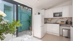 Une cuisine moderne avec des meubles blancs, un réfrigérateur, un four à micro-ondes et un évier.
