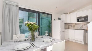 Une cuisine moderne avec des meubles blancs, un plan de travail en marbre et un coin repas avec une table dressée pour quatre personnes.