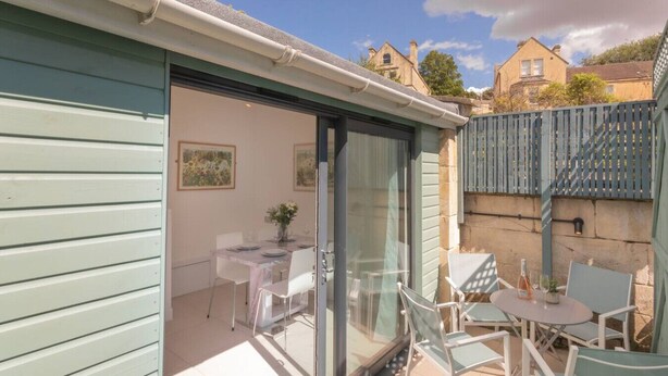 Une terrasse avec une table et des chaises, une porte-fenêtre coulissante et une vue sur les environs.