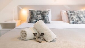 Un lit bien fait, avec des serviettes pliées et un oreiller, une table de chevet avec une lampe et un tableau encadré au mur.
