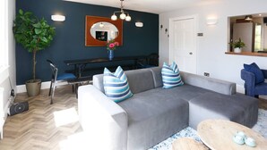 A modern living room with a grey sofa, striped pillows, a wooden coffee table, and a potted plant. - Georgian Apartment near Royal Crescent (Bath and North East Somerset)