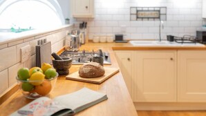Una cocina moderna con encimera de madera, un cuenco de limones, hogaza de pan y un periódico.