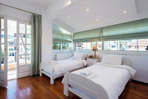 Una habitación de hotel con dos camas, un ventanal con vistas y una puerta que da al exterior.