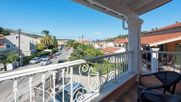 A balcony with a view of a street, cars, and buildings.