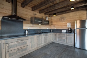 Una cocina moderna con armarios de madera, un refrigerador de acero inoxidable y una campana extractora negra.