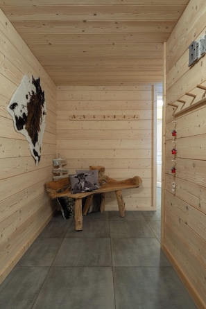 Een houten interieur met een bank, een leren vacht en een bord aan de muur.