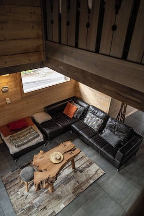 Een modern ingerichte blokhut met een leren hoekbank, een houten salontafel en een rustiek vloerkleed.