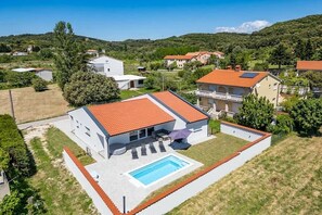 Il s’agit d’une propriété résidentielle dotée d’une piscine, d’un patio couvert et offrant une vue sur les maisons et les collines environnantes.