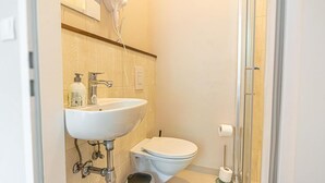 A bathroom with a sink, toilet, and a hairdryer on the wall. - Chic Room with Private Bath | Mariahilferstraße (Vienna)