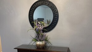 A dark wooden console table with a vase of flowers against a light blue wall.