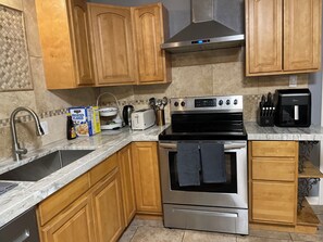 A kitchen with wooden cabinets, a stainless steel stove, a coffee maker, and a toaster.