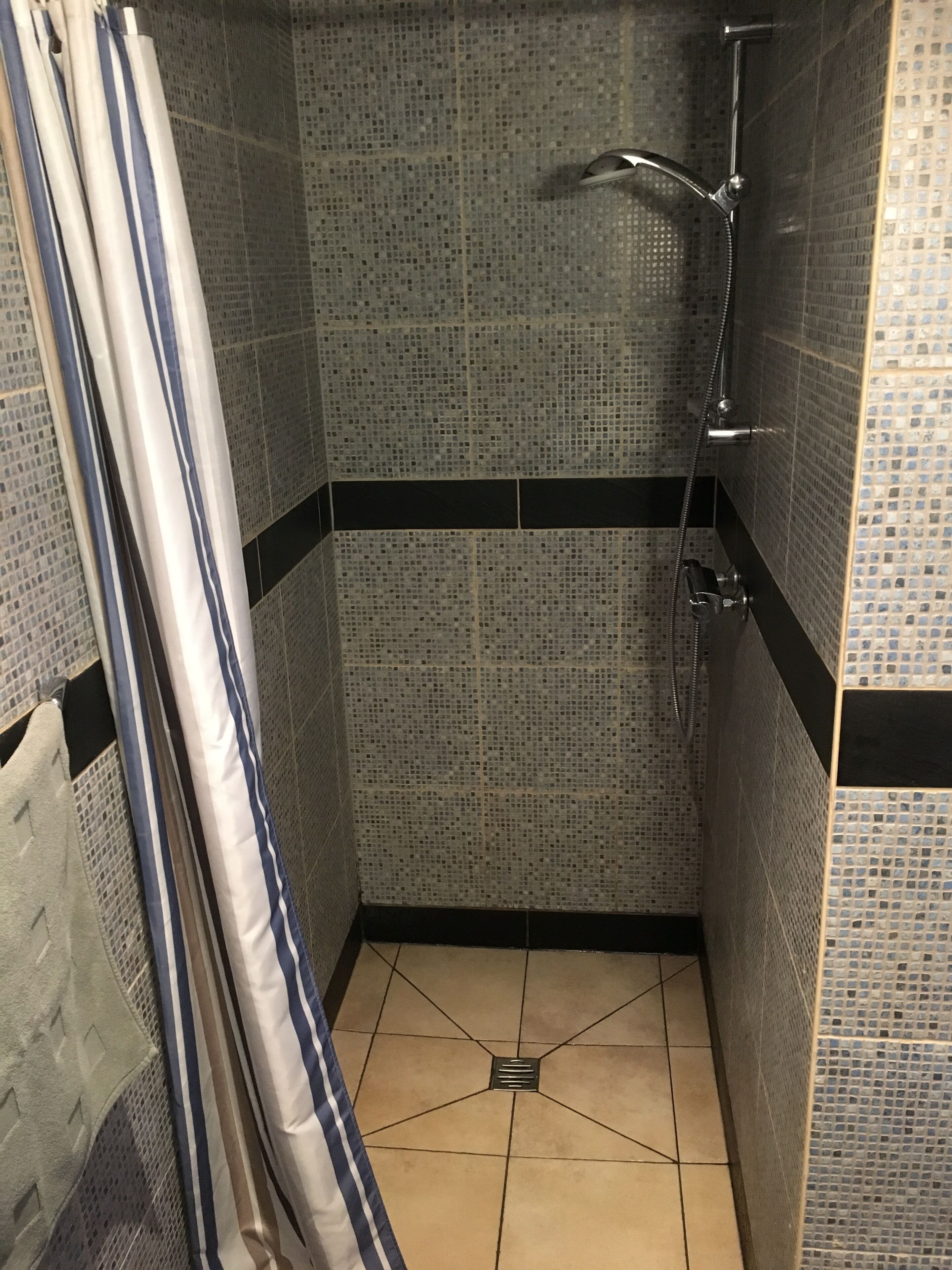 Un espace douche avec des murs recouverts de mosaïques et un sol carrelé.