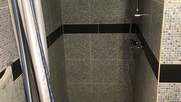 Un espace douche avec des murs recouverts de mosaïques et un sol carrelé.