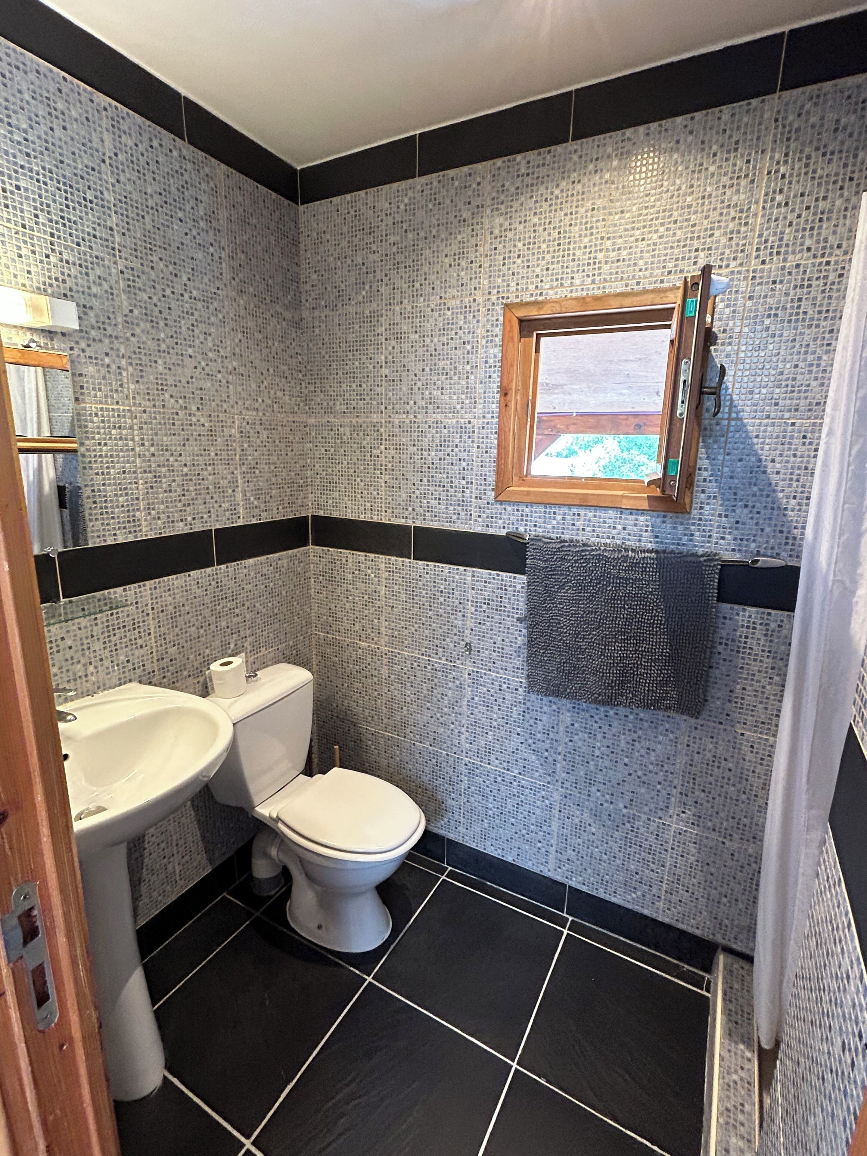 Une salle de bain avec des toilettes, un lavabo et une petite fenêtre.