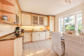 A kitchen with white cabinets, a countertop, and a dining area with wicker chairs.