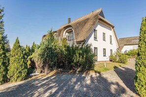A house with a unique thatched roof, a paved driveway, and a sign indicating a parking area.