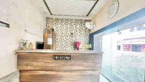 A reception desk with a "RECEPTION" sign, a clock, and a wall with a leaf pattern.