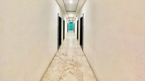 A long, narrow hallway with a marble floor and doors on both sides.