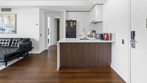 Eine moderne Küche mit einer zentralen Kochinsel, weißen Schränken und einem schwarzen Kühlschrank.