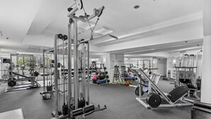 Ein Fitnessstudio mit verschiedenen Trainingsgeräten, Spiegeln und einem Teppichboden.