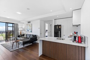 Una cocina moderna con isla integrada, un refrigerador negro y un hervidor rojo.