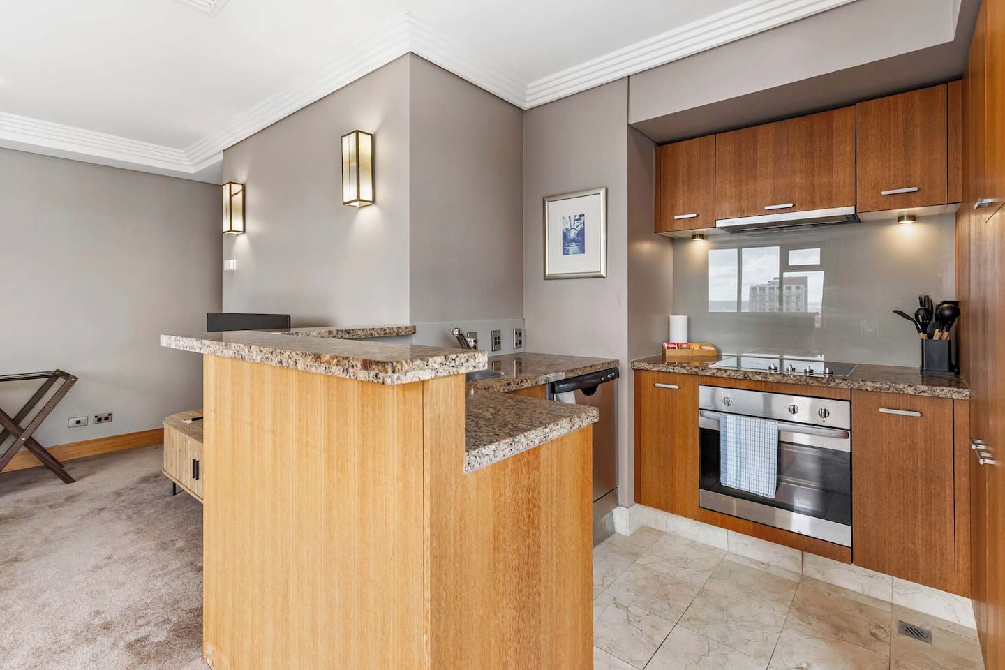 A modern kitchen with granite countertops, wooden cabinets, stainless steel appliances, and pendant lighting.
